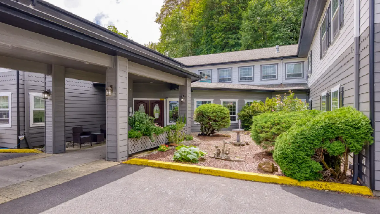 The front of a two-story building with a covered walkway and a landscaped garden with a birdbath