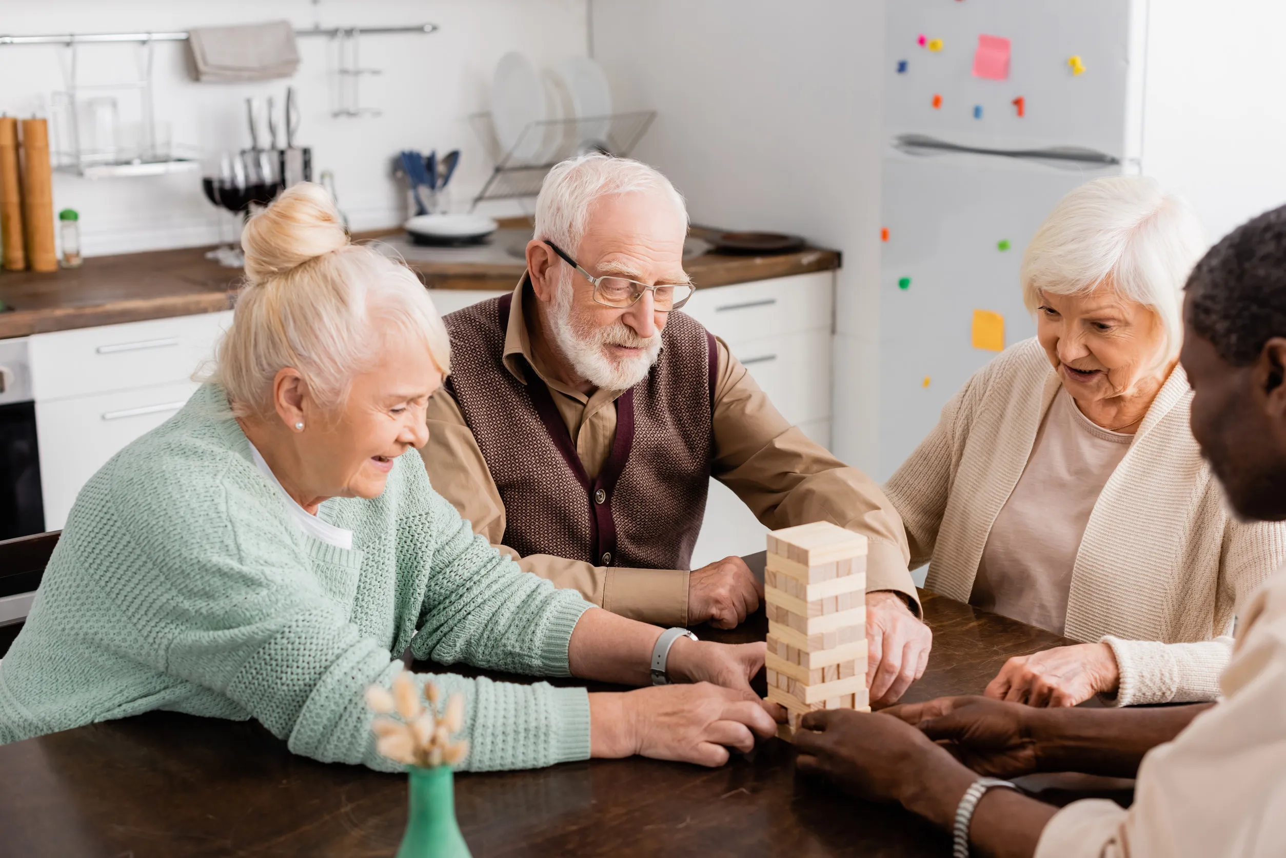 cheerful interracial pensioners smiling while playing tower wood blocks game at home